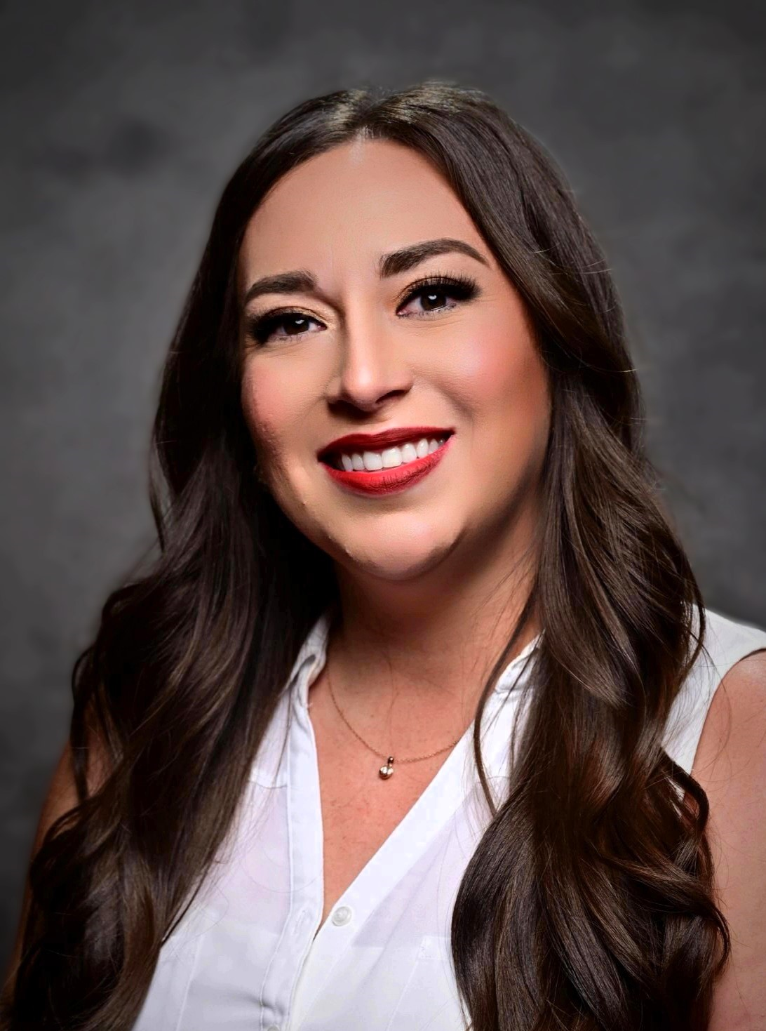 Renee, Latina woman with long brown hair, and a bright red lipstick, smiles for a headshot.