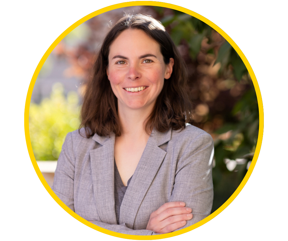 Lauren, a young woman with light skin and shoulder length brown hair, smiles wearing a tweed blazer.